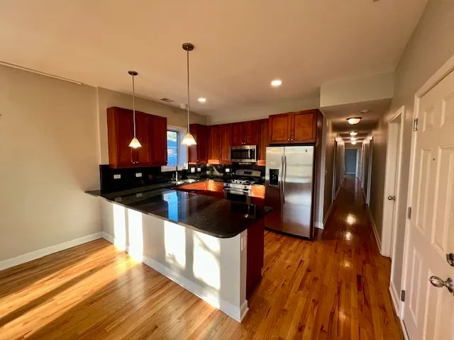 a kitchen with stainless steel appliances granite countertop a sink a stove and a refrigerator