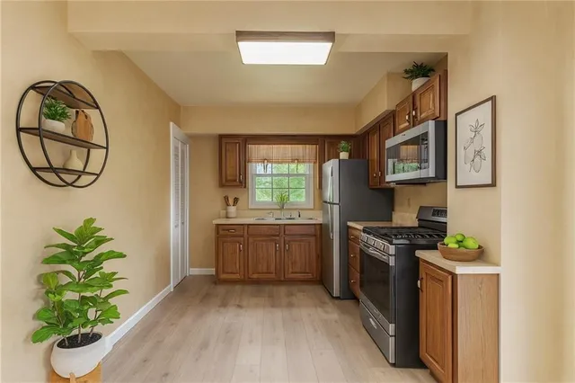 a kitchen with stainless steel appliances a white stove top oven a sink a counter space and a window