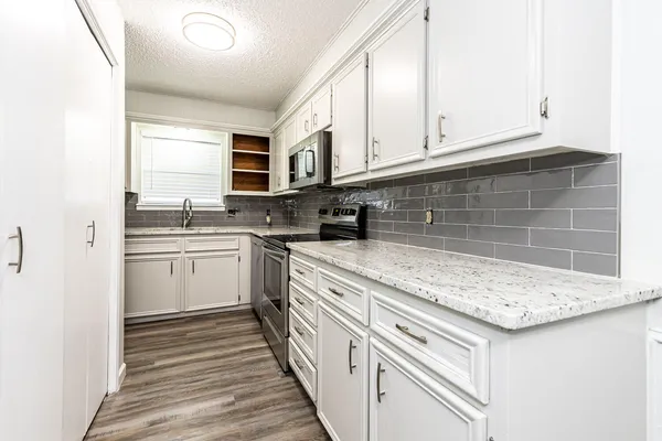a kitchen with stainless steel appliances granite countertop a sink and dishwasher a stove with white cabinets