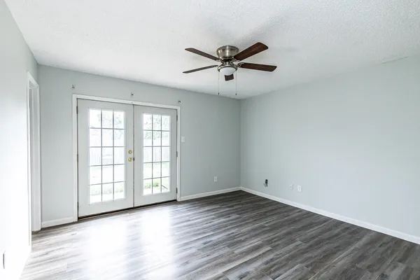 a view of an empty room with wooden floor and a window
