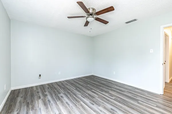 an empty room with a ceiling fan and wooden floor