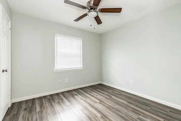 an empty room with a window and a ceiling fan