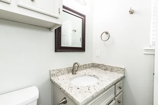 a bathroom with a granite countertop sink and a mirror