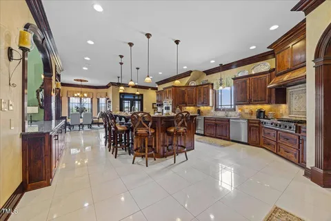 a large kitchen with stainless steel appliances granite countertop a large counter top a stove and a chandelier