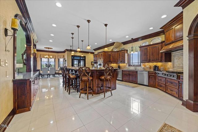 a large kitchen with stainless steel appliances granite countertop a large counter top a stove and a chandelier