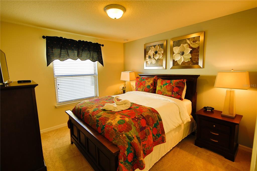 8809 Rhodes Street Kissimmee, FL 34747 - Photo 12 of 49 a bed sitting in a bedroom next to a lamp