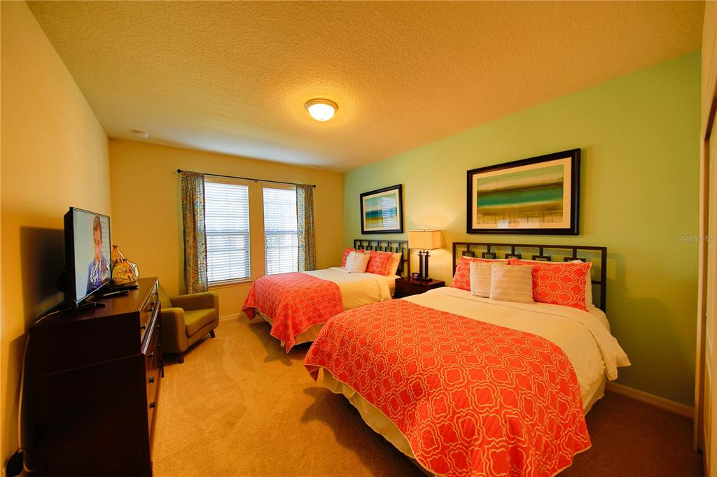 8809 Rhodes Street Kissimmee, FL 34747 - Photo 21 of 49 a bedroom with two beds and a flat screen tv