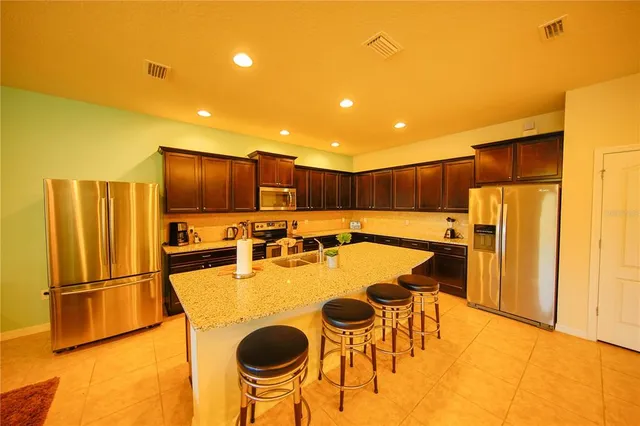 a kitchen with stainless steel appliances kitchen island granite countertop a table and chairs in it