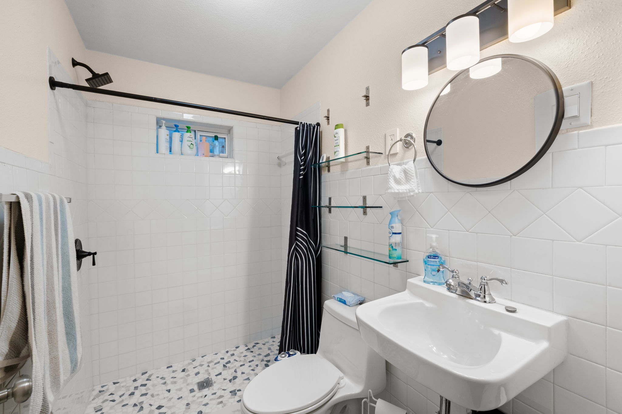 907 East 53rd Street Austin, TX 78751 - Photo 15 of 36 A well-lit primary bathroom featuring a tile-surrounded walk-in shower and wall-mounted sink.