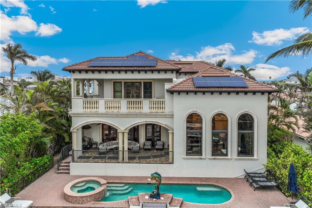 280 Egret Avenue Naples, FL 34108 - Photo 36 of 44 The back of the house features solar panels, a swimming pool with hot tub, a balcony, and a patio