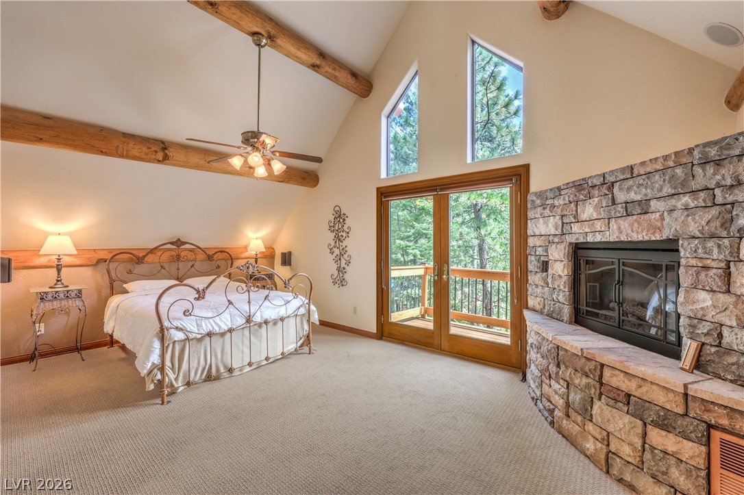 322 Ski Trail Road Mount Charleston, NV 89124 - Photo 19 of 58 High vaulted ceilings with exposed log beams frame a cozy stone fireplace and private balcony access.