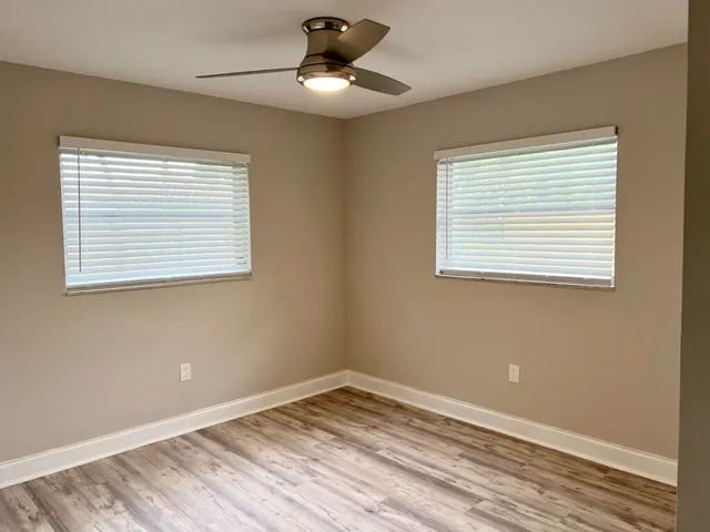 a view of an empty room with wooden floor and a window