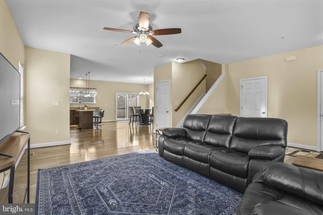 a living room with furniture wooden floor and a ceiling fan