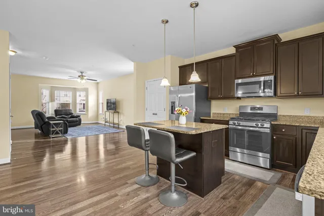a kitchen with kitchen island granite countertop wooden floors and wooden cabinets