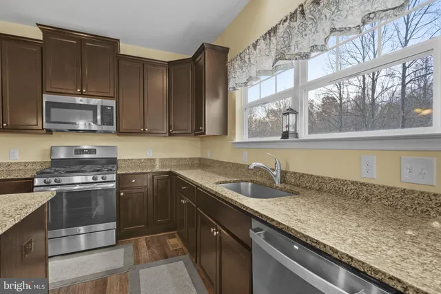 a kitchen with stainless steel appliances granite countertop a sink stove and microwave