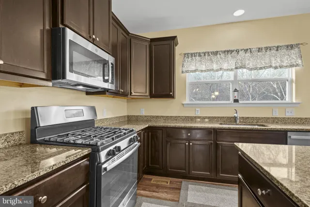 a kitchen with stainless steel appliances granite countertop a sink stove and microwave