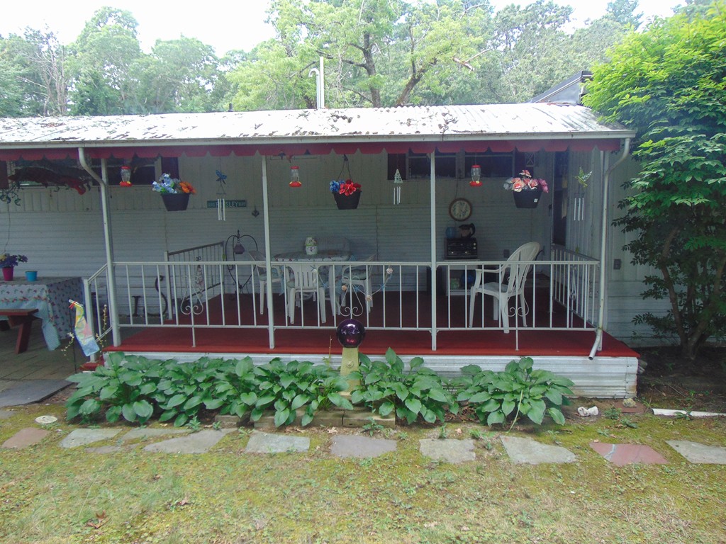 3132 Cranberry Highway, Unit 56 Wareham, MA 02538 - Photo 5 of 20 a view of a house with a wooden deck and a yard