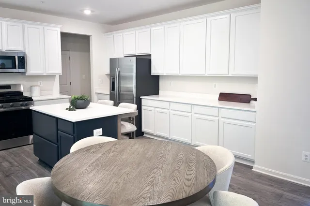 a kitchen with stainless steel appliances granite countertop a dining table chairs refrigerator sink and cabinets