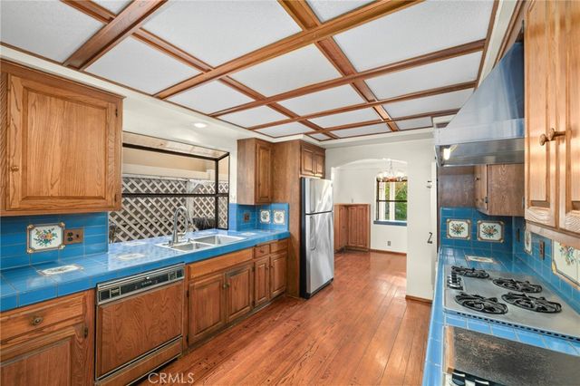 a kitchen with stainless steel appliances granite countertop a sink and wooden floors