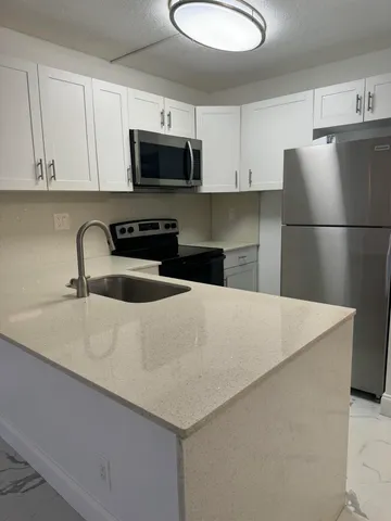 a kitchen with stainless steel appliances a microwave a sink a stove and white cabinets