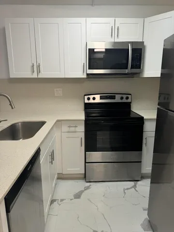 a kitchen with granite countertop a stove microwave and sink