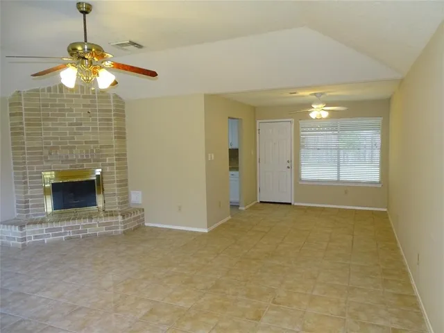 a view of an empty room with a fireplace and a window