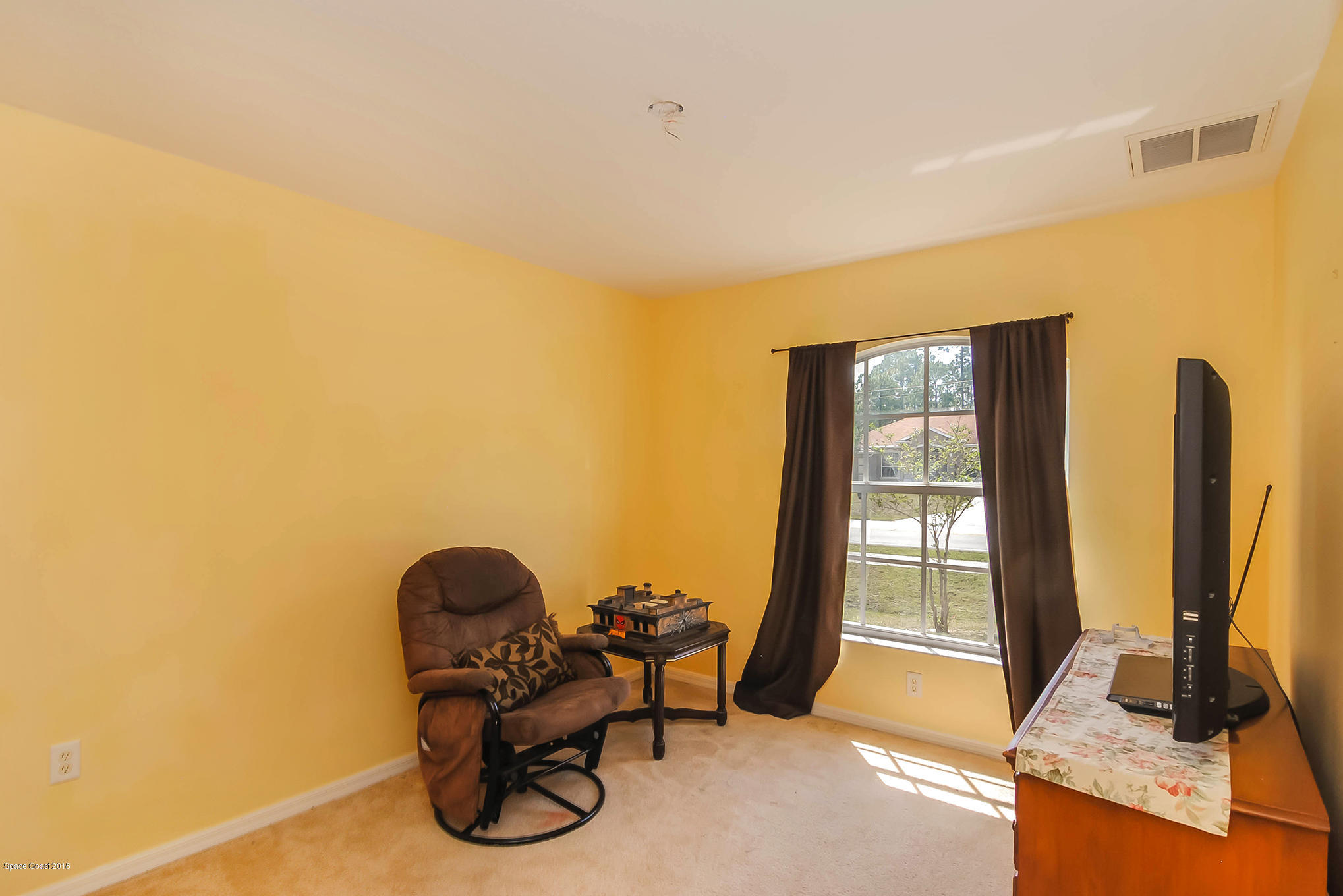1317 Degroodt Road Southwest Palm Bay, FL 32908 - Photo 20 of 26 a living room with furniture a floor to ceiling window and a flat screen tv