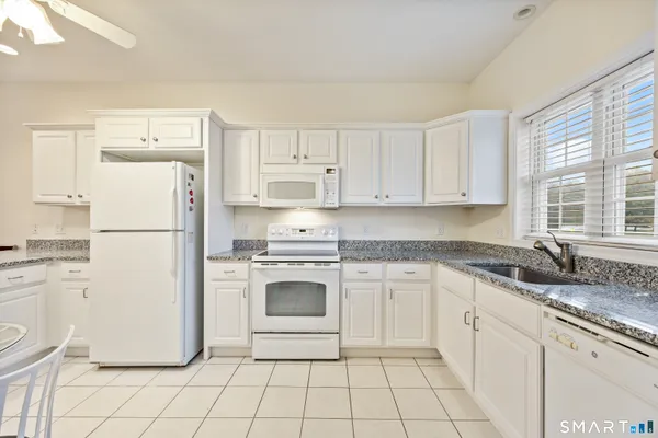 a kitchen with white cabinets and white appliances