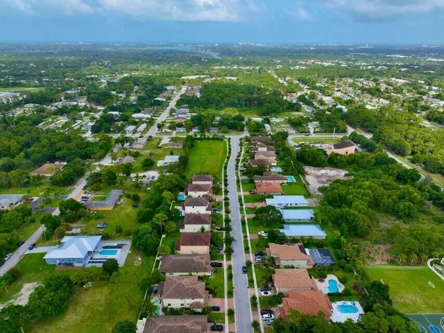 an aerial view of residential houses with outdoor space and trees