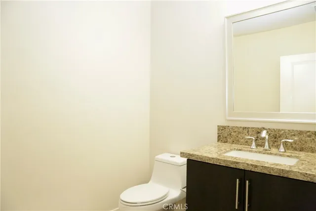 a bathroom with a granite countertop sink and a toilet