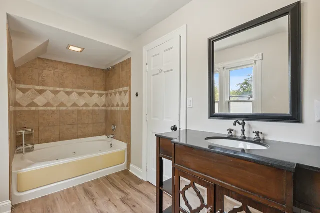 a bathroom with a bathtub shower sink and a mirror