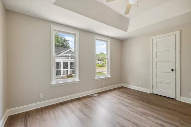 an empty room with wooden floor and windows