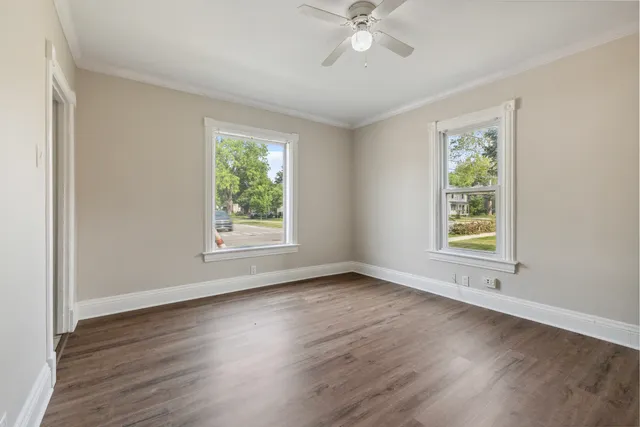 a view of an empty room with wooden floor and window