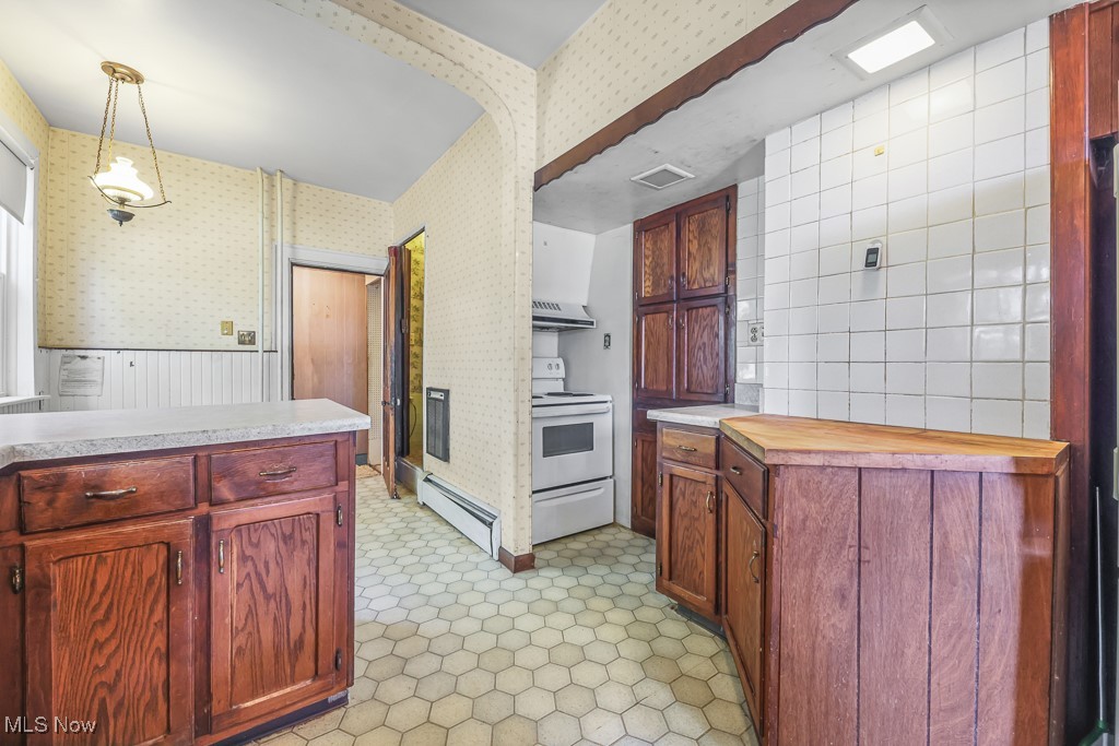 6727 Waterloo Road Atwater, OH 44201 - Photo 21 of 48 Kitchen featuring white electric range, hanging light fixtures, a baseboard radiator, exhaust hood, and butcher block counters