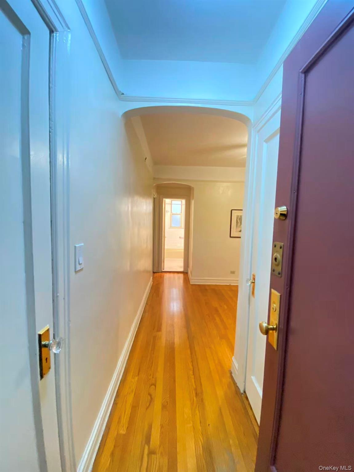 79-15 35th Avenue, Unit 3C Queens, NY 11372 - Photo 3 of 13 Hallway with arched walkways and light wood finished floors
