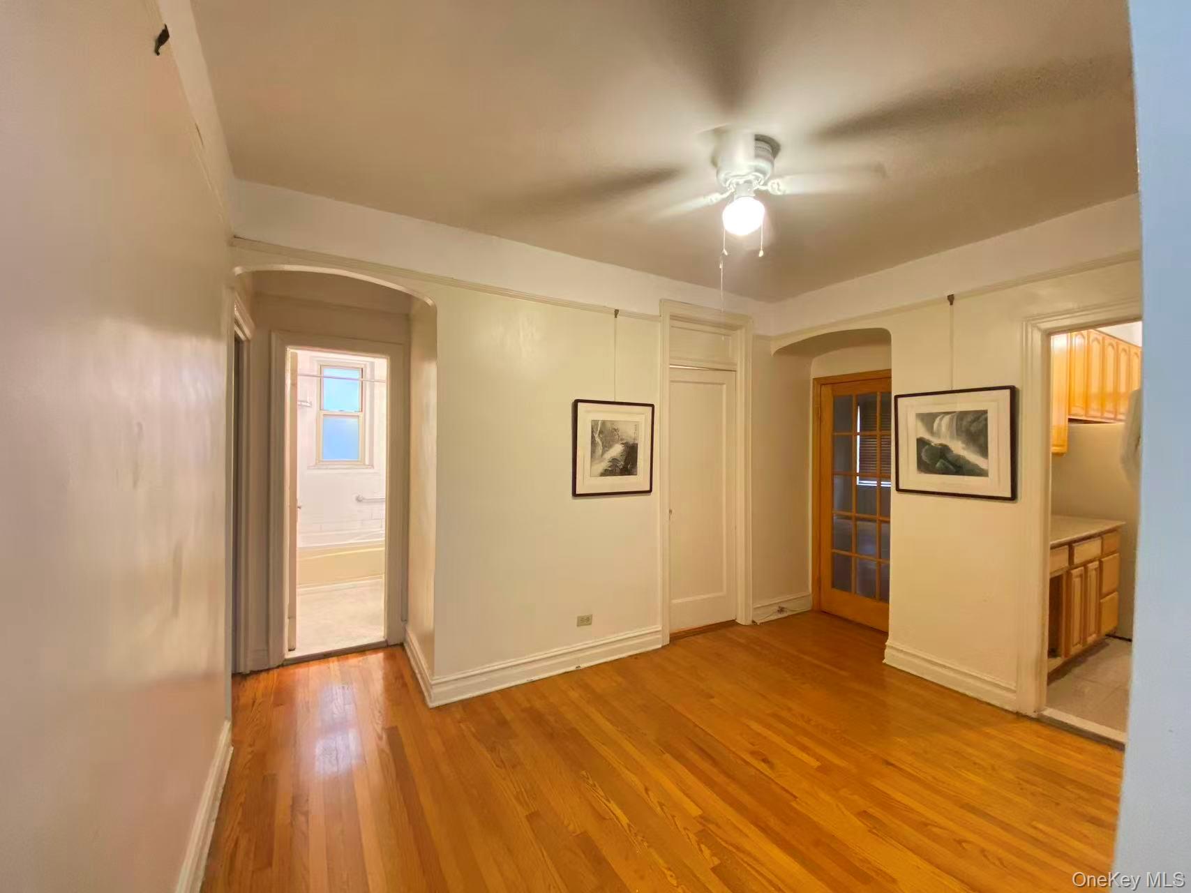 79-15 35th Avenue, Unit 3C Queens, NY 11372 - Photo 4 of 13 Spare room with arched walkways, light wood finished floors, and ceiling fan