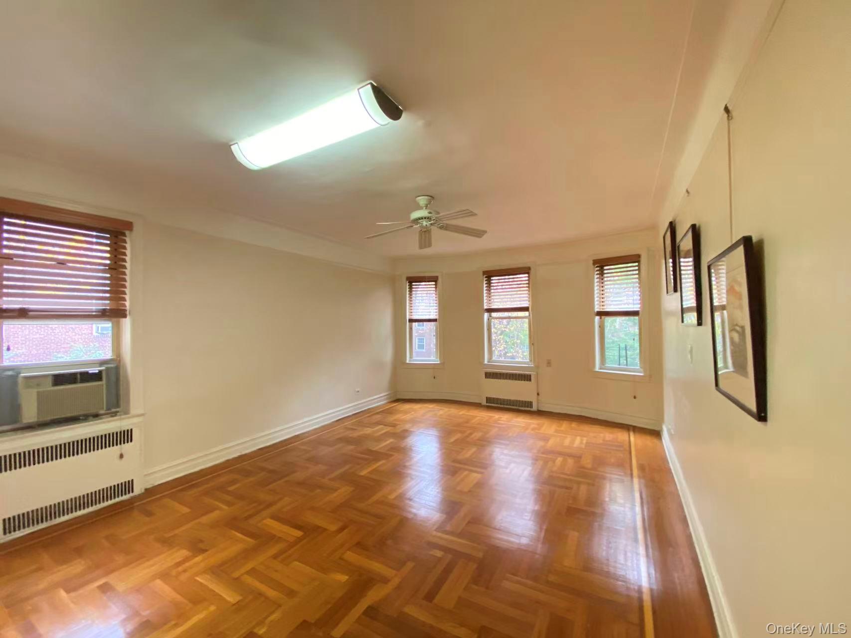 79-15 35th Avenue, Unit 3C Queens, NY 11372 - Photo 9 of 13 Empty room featuring radiator, plenty of natural light, and ceiling fan