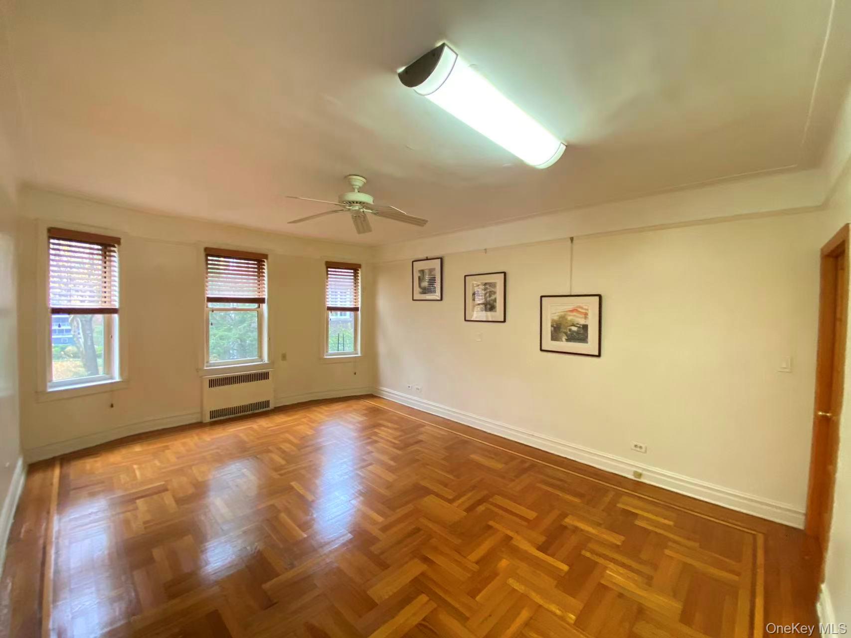 79-15 35th Avenue, Unit 3C Queens, NY 11372 - Photo 10 of 13 Empty room featuring radiator heating unit and a ceiling fan