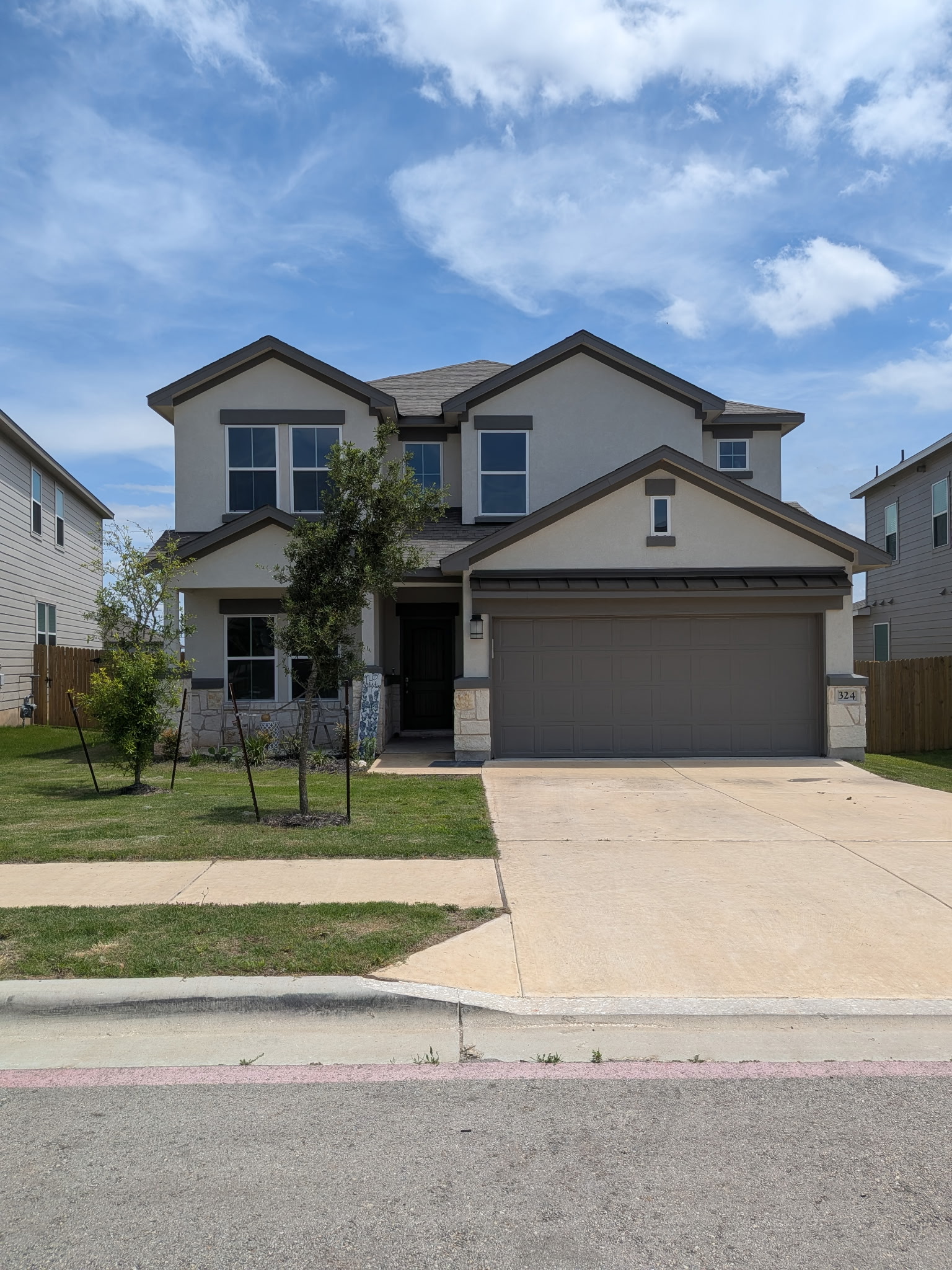 324 Windstar Road Liberty Hill, TX 78642 - Photo 1 of 6 Two-story stucco and stone exterior featuring a two-car garage, multiple gabled rooflines, and a concrete driveway