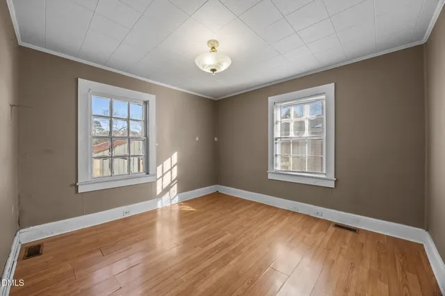 a view of an empty room with wooden floor and a window