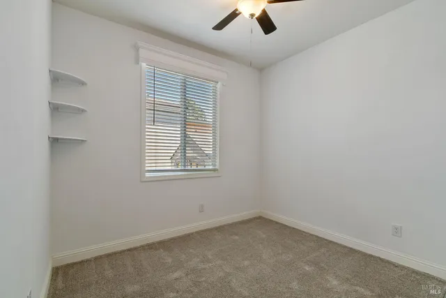 an empty room with a window and a ceiling fan