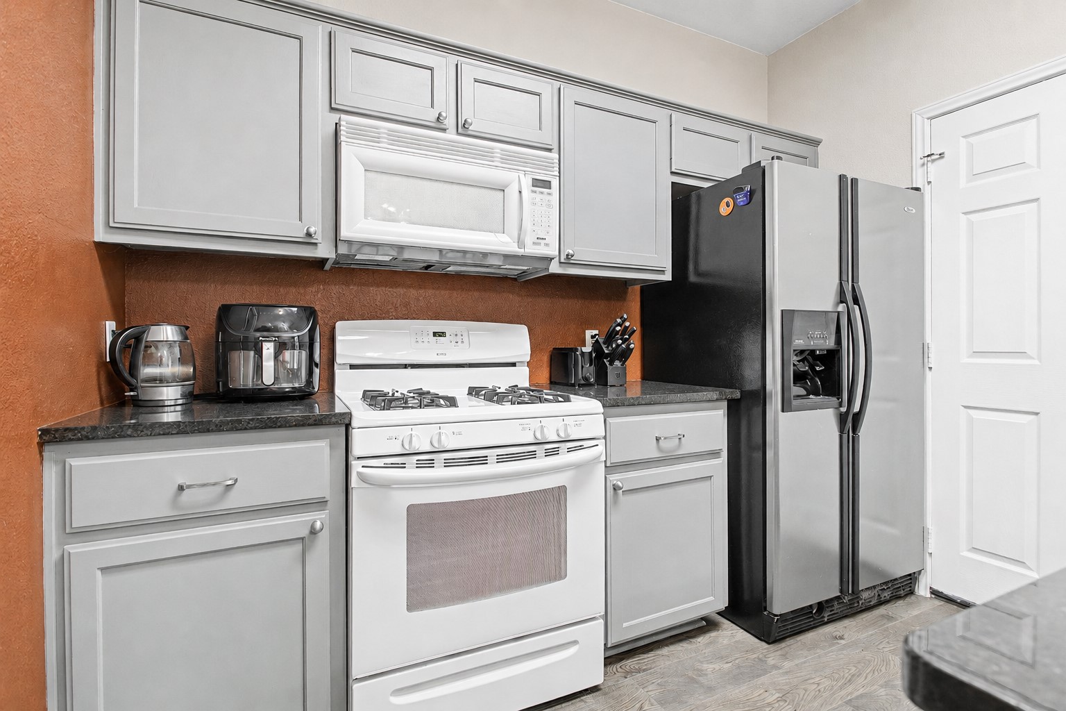207 Kates Way Hutto, TX 78634 - Photo 5 of 24 Kitchen featuring gray cabinetry, dark countertops, white gas range, stainless steel French door refrigerator, and wood-finish flooring.
Photo digitally edited to remove personal items.