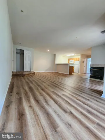 a view of a livingroom with wooden floor and an empty room