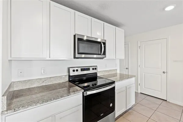 a kitchen with granite countertop white cabinets and stainless steel appliances