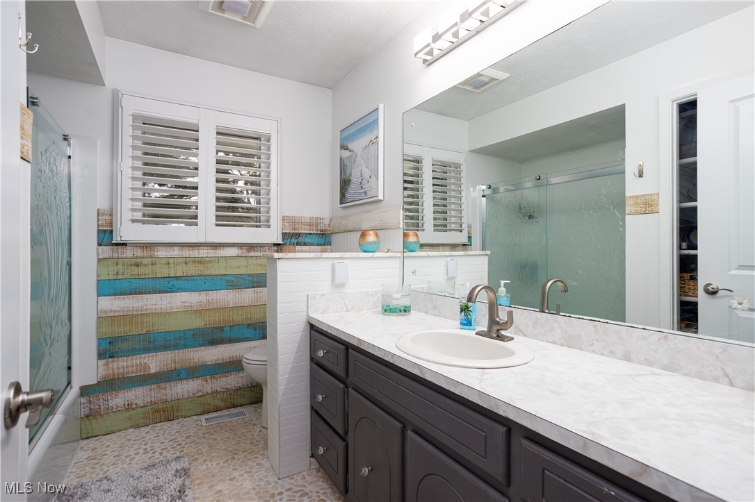7317 Beach Road Wadsworth, OH 44281 - Photo 16 of 42 Bathroom with walk in shower, vanity, toilet, and tile walls