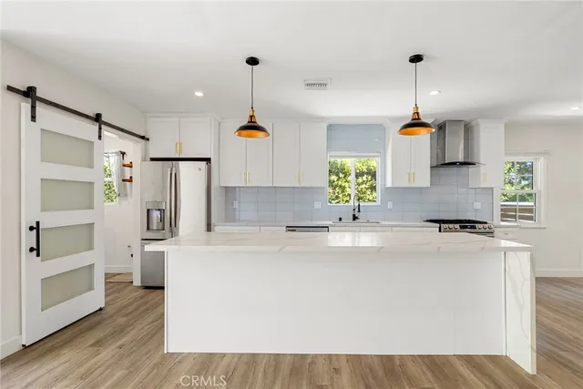 a kitchen with kitchen island white cabinets and refrigerator