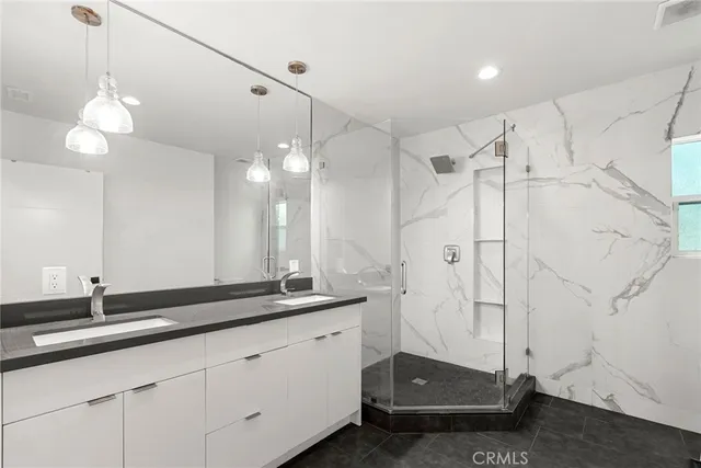 a bathroom with a double vanity sink mirror and shower