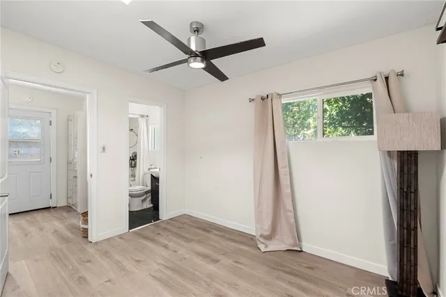 an empty room with wooden floor cabinet and windows