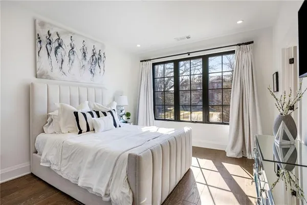 a bedroom with a large bed and a large window with wooden floor