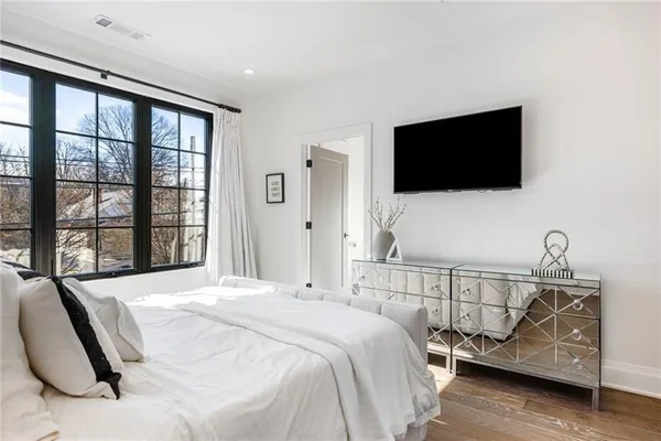 a bedroom with a bed a flat screen tv and a large window